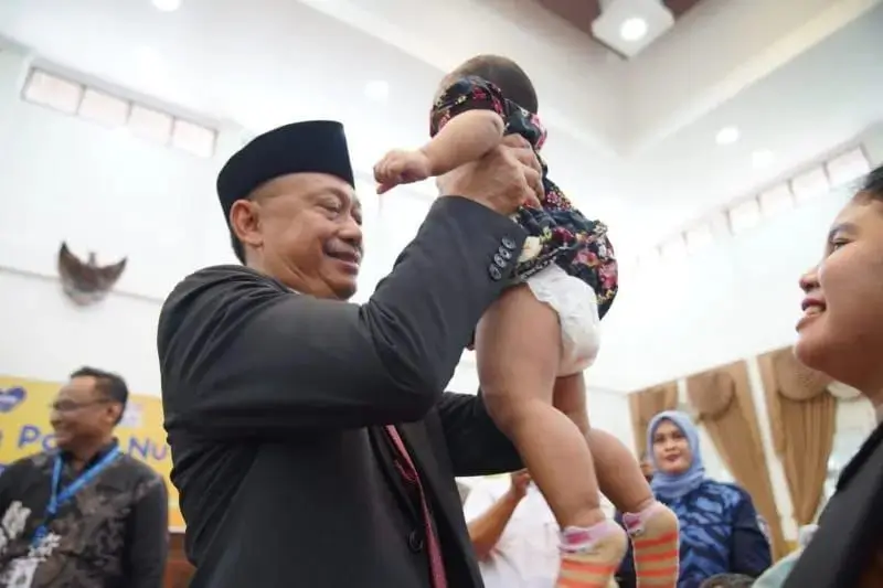 Wali Kota Pontianak Edi Rusdi Kamtono menggendong balita sebelum ditimbang berat badannya dalam kegiatan imunisasi anak.