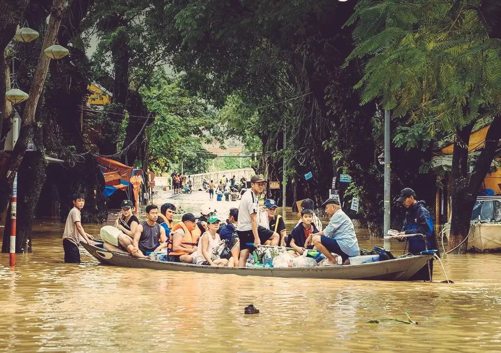 Warga dan wisatawan menaiki perahu melintasi kawasan kota tua Hoi An, Vietnam, yang masih tergenang banjir. (x.com/TheCBIJ)