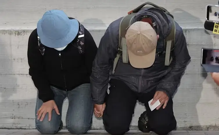 Orang tua pelaku penusukan massal Metro Taipei berlutut meminta maaf di rumah duka. (Dok. AFP)