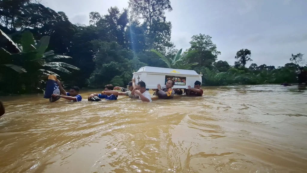 Petugas bersama warga menggotong peti jenazah menembus banjir di Beduai, Sanggau. (Dok. Nuansa Kalbar)