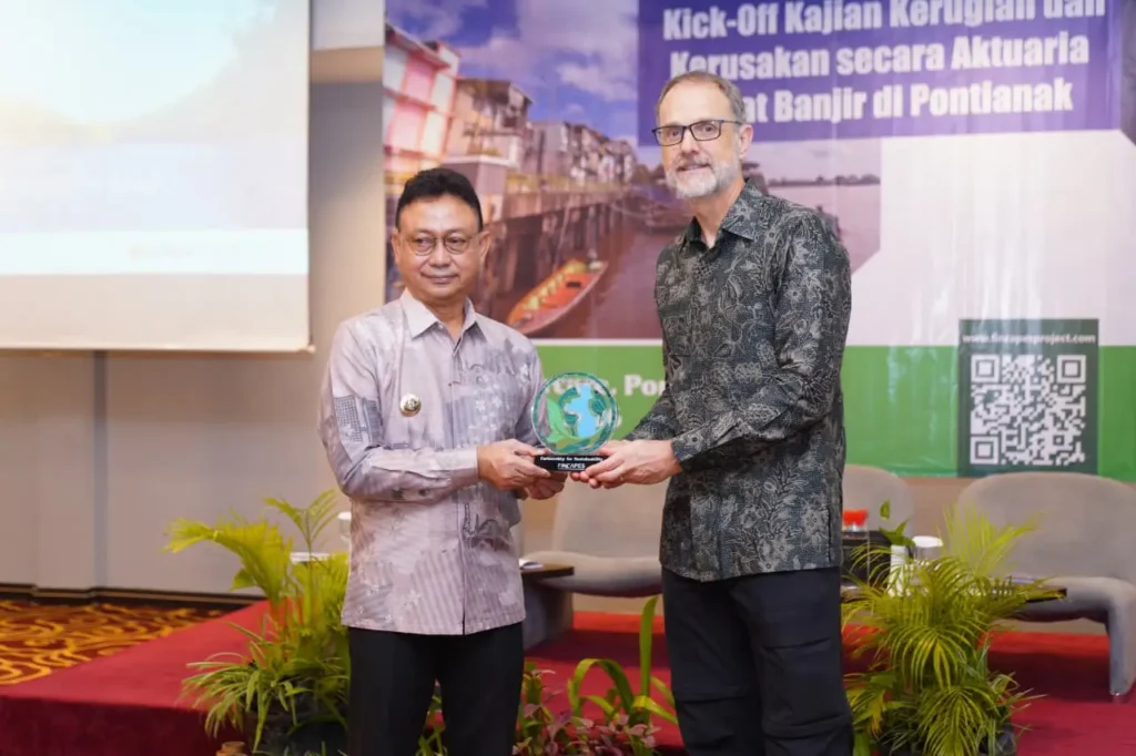 Wali Kota Pontianak, Edi Rusdi Kamtono menerima cinderamata kolaborasi dari perwakilan Universitas Waterloo Kanada, Prof. Stefan Steiner usai membuka Kick Off Kajian Kerugian dan Kerusakan secara Aktuaria Akibat Banjir di Pontianak, di Hotel Mercure, Kamis (15/1/2026).