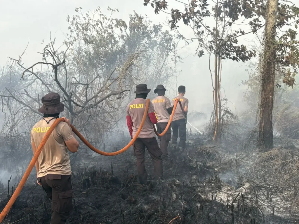 Petugas gabungan memadamkan titik api kebakaran lahan di wilayah Pontianak Selatan, Senin (26/1). (Foto: Polresta Pontianak)