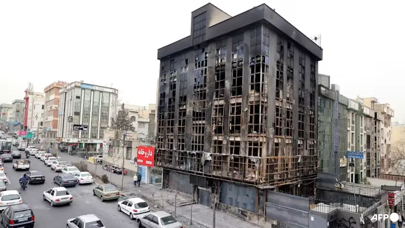 Warga berjalan melewati bangunan yang terbakar dan rusak parah akibat protes massa di Teheran, Iran, 19 Januari 2026.