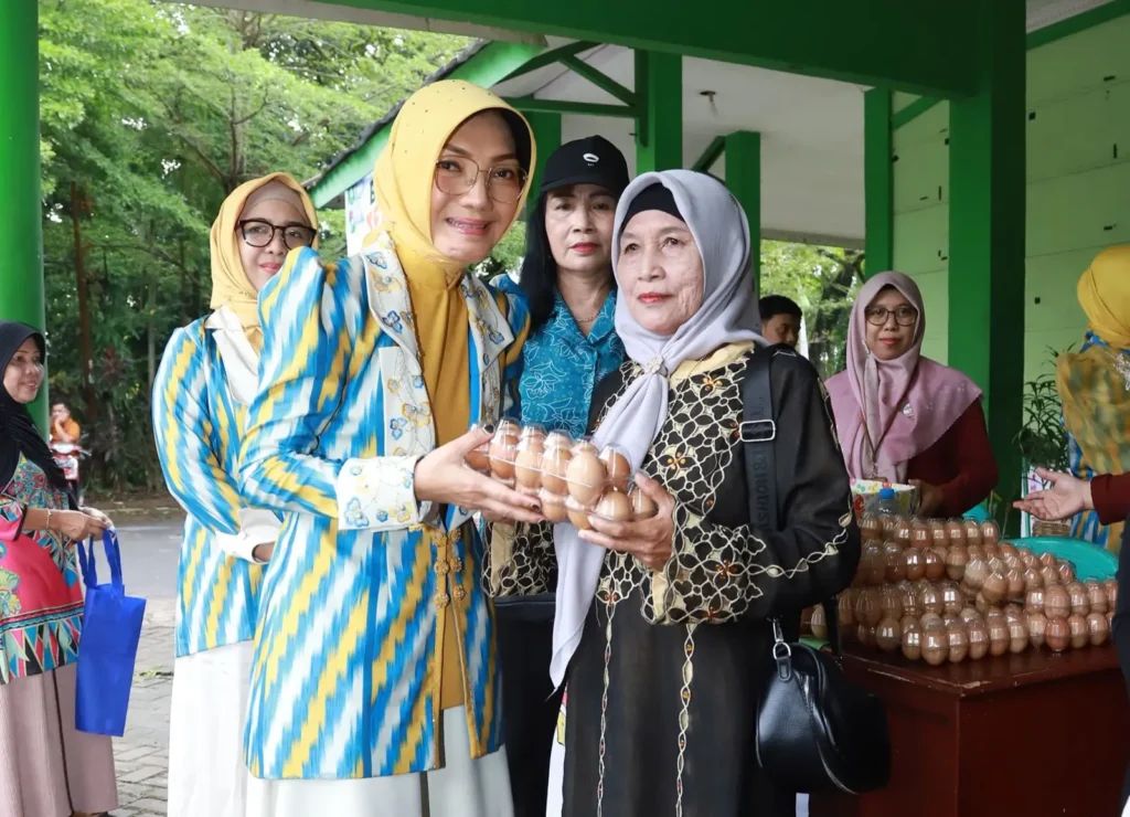 Ketua TP PKK Kota Pontianak Yanieta Arbiastutie menyerahkan secara simbolis telur ayam kepada warga yang berbelanja di bazar murah telur.