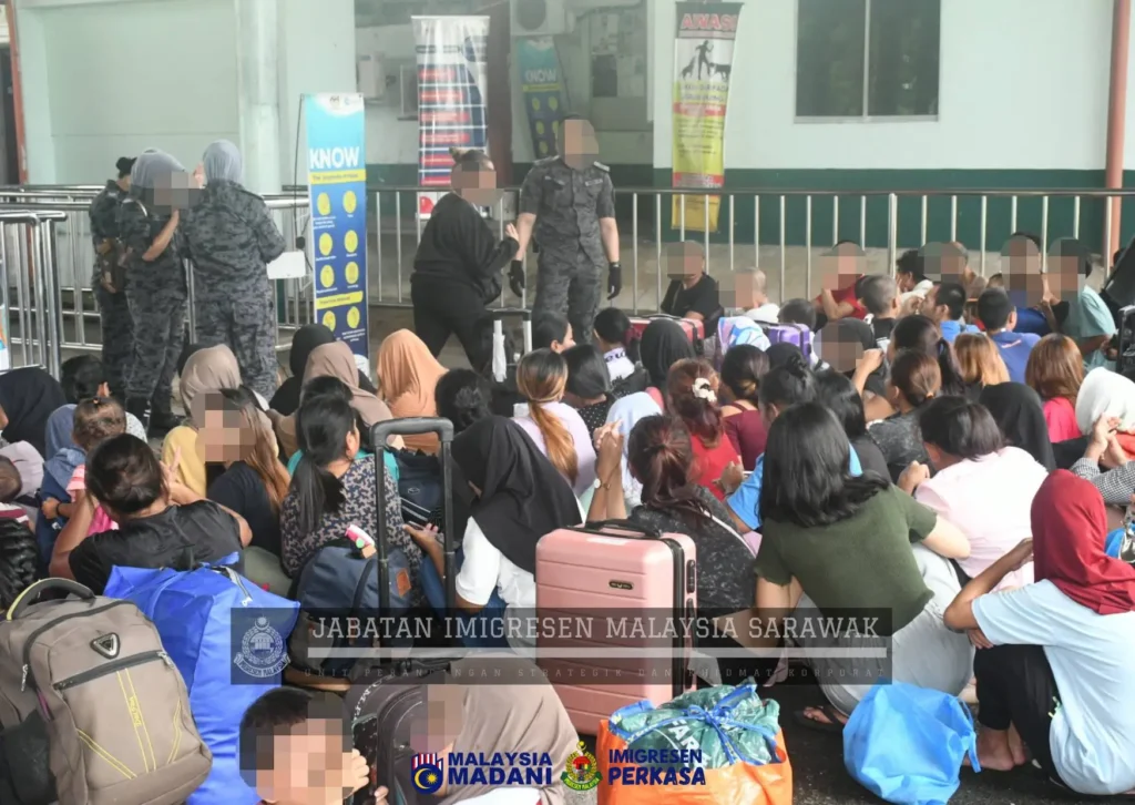 Petugas JIM Sarawak bersama ratusan WNI yang dideportasi ke Indonesia melalui Depot Imigresen Semuja.