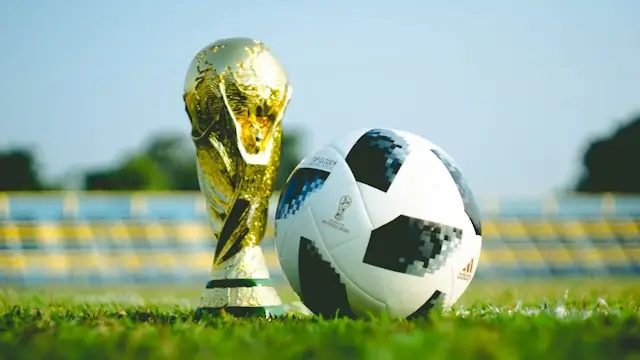 Ilustrasi trofi Piala Dunia FIFA 2026 dengan latar stadion sepak bola internasional dan logo turnamen.