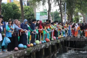 Para siswa-siswi SMP Negeri 1 antusias menaburkan cairan eco enzyme di parit Jalan HOS Cokroaminoto.