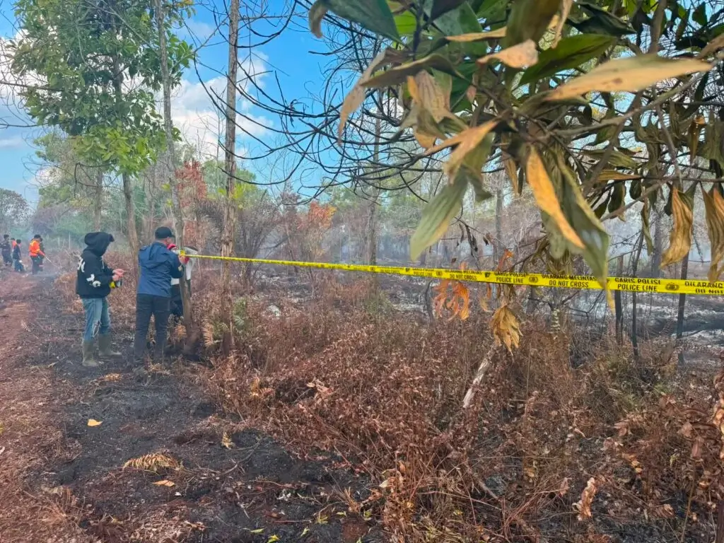 Petugas Polres Kubu Raya memasang police line di lokasi kebakaran hutan dan lahan di Desa Parit Baru, Kecamatan Sungai Raya, untuk kepentingan penyelidikan.