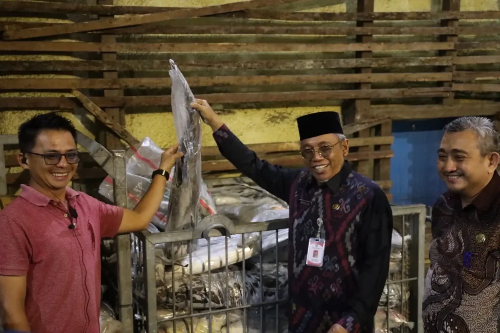 ⁠Sekretaris Daerah Kota Pontianak Amirullah memperlihatkan ikan bersama pemilik gudang.