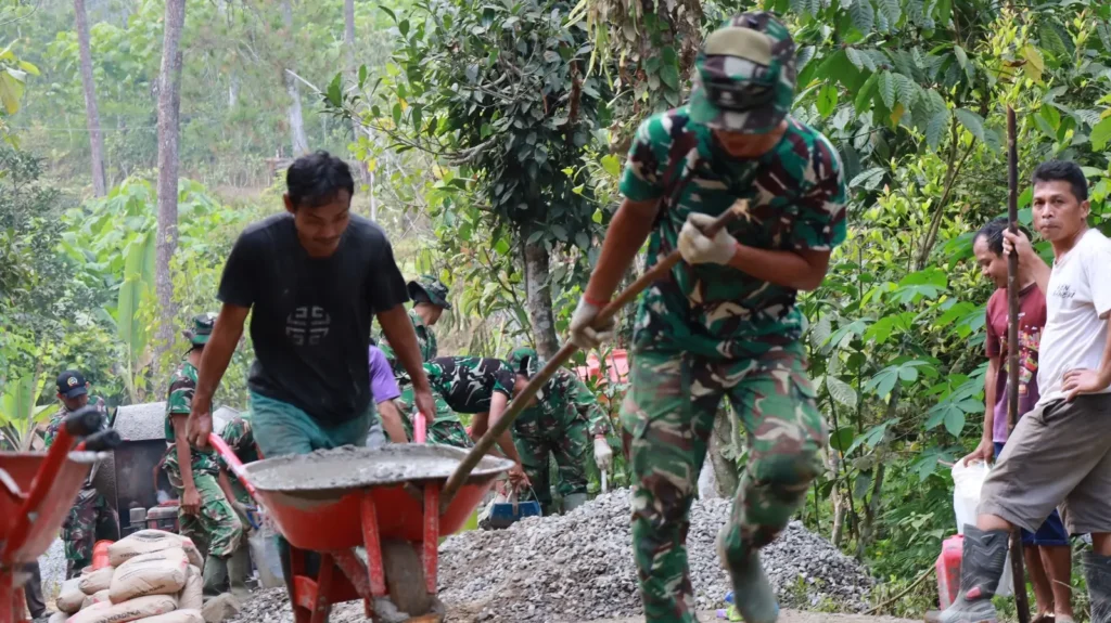 Anggota Satgas TMMD bersama warga menarik arko bermuatan material menggunakan kayu bercabang di medan terjal Desa Watuduwur, Purworejo.