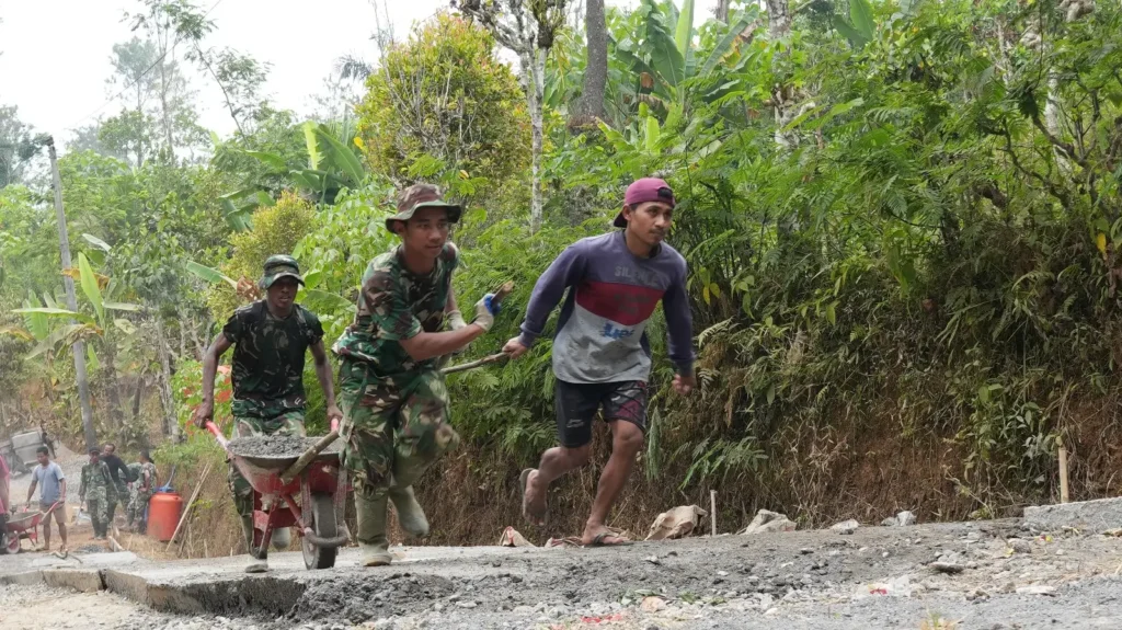Satgas TMMD bersama warga menarik arko berisi material saat melintasi medan terjal untuk mendukung pengecoran jalan di Desa Watuduwur, Purworejo.