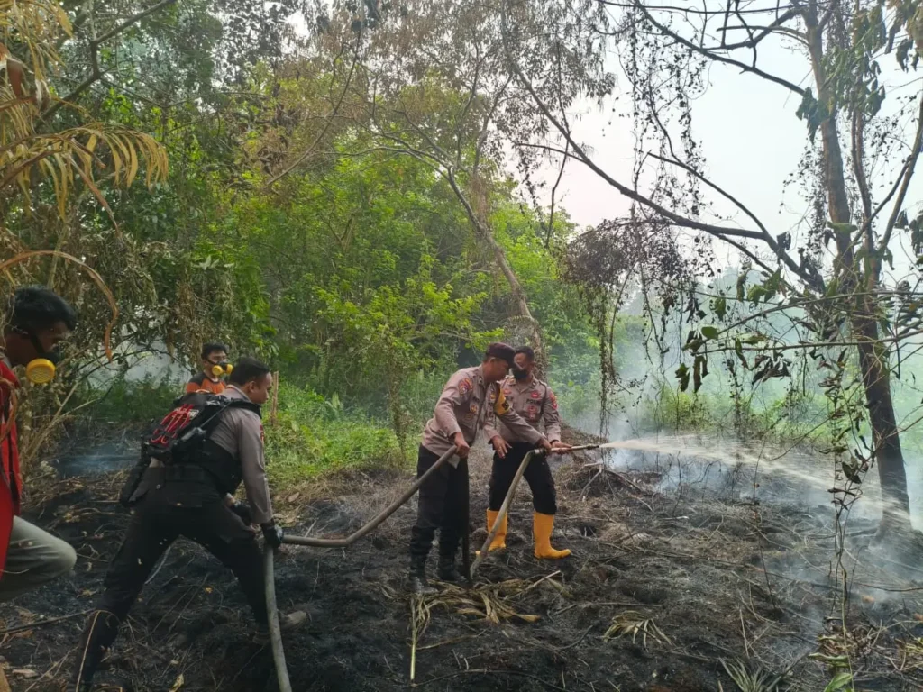 Petugas Polresta Pontianak bersama tim pemadam kebakaran memadamkan titik api karhutla di Jalan Bina Jaya, Gang Batas Damai. (Foto: Polresta Pontianak)