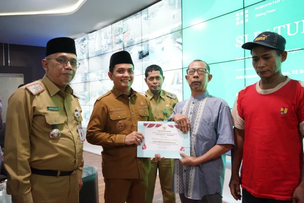 Wakil Wali Kota Pontianak Bahasan menyerahkan penghargaan kepada pedagang tercepat melakukan pembayaran retribusi pasar saat peluncuran SI PATUH PASAR di Pontive Center, Selasa (22/9/2026).