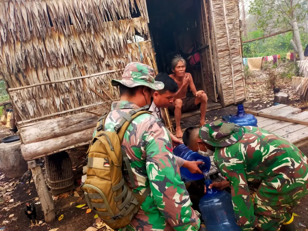 Petugas menyalurkan air bersih kepada lansia di sela pemadaman karhutla di Kayong Utara. (Foto: Res-KKU)