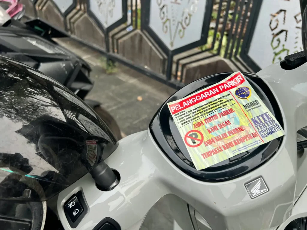 Petugas Dishub Pontianak menempelkan stiker peringatan pada kendaraan yang parkir di trotoar saat pelaksanaan Car Free Day (CFD) di Kota Pontianak, Minggu (4/10/2026).