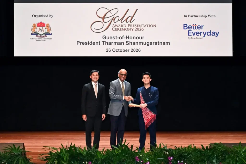 Nathan Alexandro Tjhe (kanan), pelajar asal Pontianak, Kalimantan Barat, menerima penghargaan Gold National Youth Achievement Award (NYAA) 2026 dari Presiden Singapura Tharman Shanmugaratnam (tengah), didampingi Senior Minister of State Desmond Tan (kiri), Senin (26/10/2026). (Istimewa)
