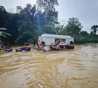 Petugas bersama warga menggotong peti jenazah menembus banjir di Beduai, Sanggau. (Dok. Nuansa Kalbar)