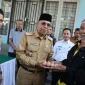 Sekretaris Daerah Kota Pontianak Amirullah menyerahkan secara 1 pak telur kepada Saripin (81), warga Pontianak Tenggara yang berbelanja di Operasi Pasar Murah.
