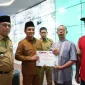 Wakil Wali Kota Pontianak Bahasan menyerahkan penghargaan kepada pedagang tercepat melakukan pembayaran retribusi pasar saat peluncuran SI PATUH PASAR di Pontive Center, Selasa (22/9/2026).