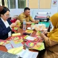 Petugas Rumah Kemasan yang berlokasi di Lantai 2 Pasar Kemuning tengah memproduksi kemasan untuk membantu pelaku UMKM.