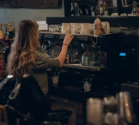 Coffee shop aesthetic Ilustrasi - Coffee shop aesthetic dengan interior minimalis, barista membuat manual brew, dan latte art kreatif sebagai tren ngopi 2025. (unsplash.com/@zdelo)